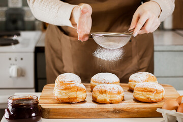 Woman prepares fresh donuts with jam in home kitchen. Cooking traditional Jewish Hanukkah sufganiyot. - obrazy, fototapety, plakaty