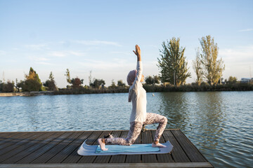 Graceful Arab woman doing Anjaneyasana pose on pier