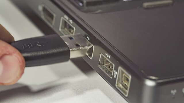 Close up of hand inserting plugging data cable into usb port in laptop 3