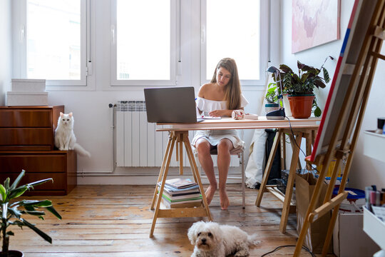 Serious woman writing notes near laptop