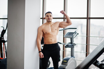 Fototapeta premium Muscular arab man in modern gym. Fitness arabian men with naked torso show his biceps.
