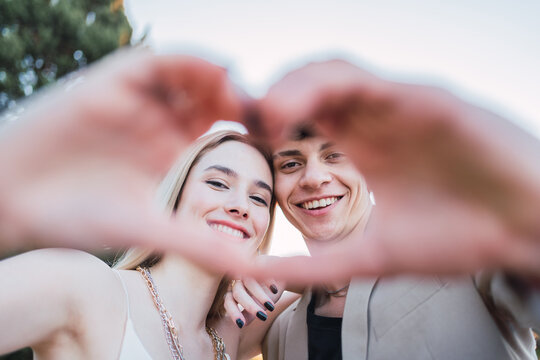 Positive couple making heart with hands in park
