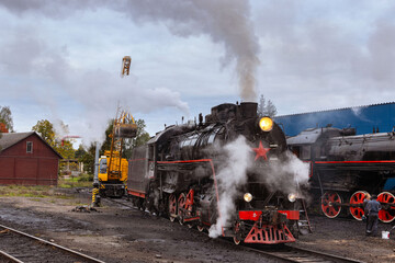 Fototapeta na wymiar Sortavala, Karelia, Russia - September 16, 2021: Crane loads coal onto steam locomotive