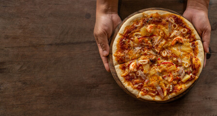 Pizza placed on a wooden tray holding it ready to serve.