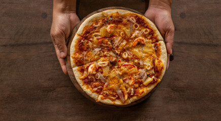 Pizza placed on a wooden tray holding it ready to serve.