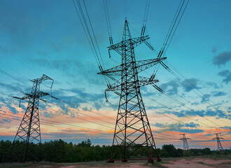 silhouette of high voltage power lines against a colorful sky at sunrise.