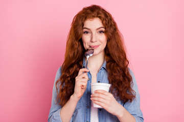 Photo of sweet hungry young woman wear denim shirt ready eat yogurt licking spoon smiling isolated pink color background - obrazy, fototapety, plakaty