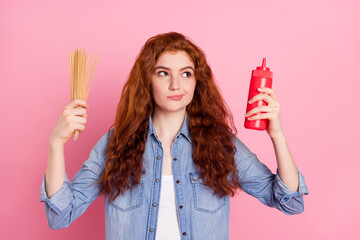Photo of minded happy positive young woman look empty space think dinner hold food isolated on pink...