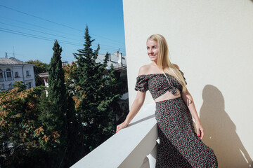 beautiful blonde woman in a gray dress looks from the balcony