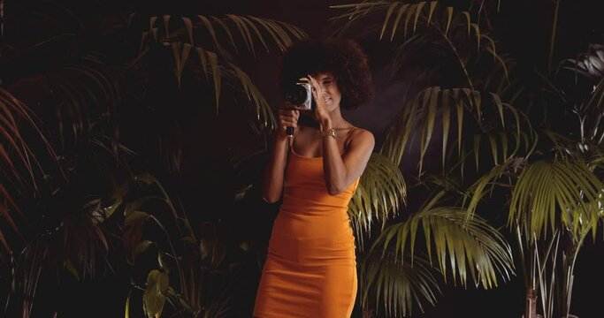 Woman With Afro Hair In Orange Dress Using Vintage 8Mm Camera