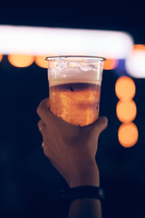 Person holding cold beer plastic cup on a music festival.