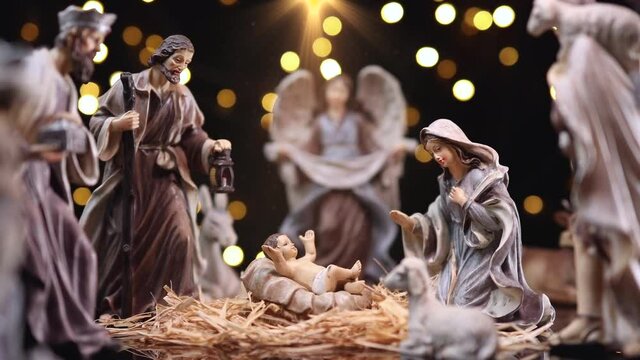 Jesus Christ Nativity scene with atmospheric lights. Jesus Christ Nativity scene with figurines and light particles. Christmas scene. Dolly shot 4k