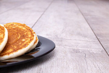 Pancakes and sour cream on plate on wooden table