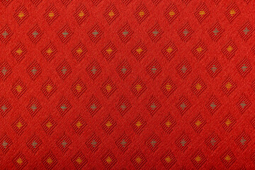 Red fabric with yellow lozenges as the background texture. Close-up long and wide texture of natural red fabric. Fabric texture of natural cotton or linen textile material. Fashion concept design