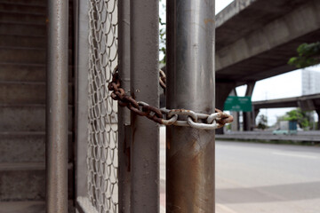 An old, rusted chain that attaches to a stainless steel pole.