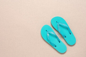 Turquoise blue flip flops. Beige paper background with splashes. Summer vacation concept. Top view,...