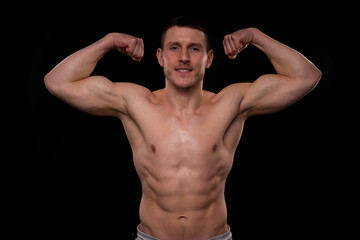 Fototapeta premium Man Showing Biceps Hands Up. Sportsman Showing Muscles. ABS, Biceps Muscles. Black Background