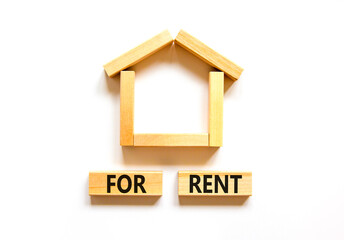 House for rent symbol. Concept words 'For rent' on wooden blocks near miniature house. Beautiful white background, copy space. Business and house for rent concept.