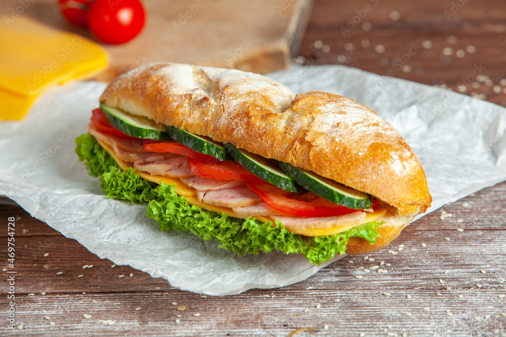 Wall mural breakfast of fresh croissant with ham, cheese and salad leaf on white wooden background.