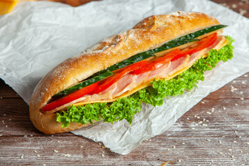 Breakfast of Fresh croissant with ham, cheese and salad leaf on white wooden background.
