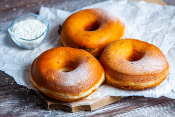 Delicious donuts with powdered sugar on wooden table