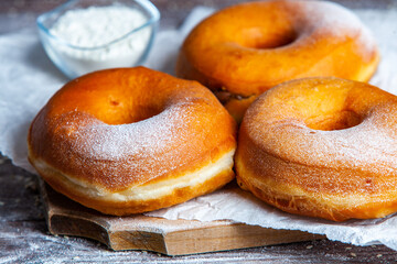 Delicious donuts with powdered sugar on wooden table