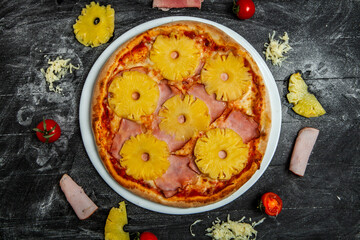 Pizza with pineapple and mozzarella on black wood background.