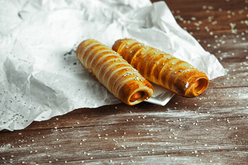 Fresh tasty sausage rolls on plate. fresh sausage in dough on wood background.