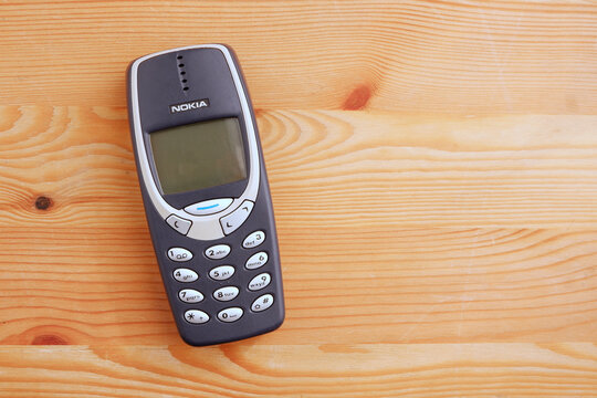 Bangkok, Thailand - November 17, 2021  Used Nokia mobile phone model 3310 with keypad on wooden floor, Copy space
