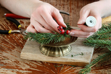 Woman shows how to make a Christmas decoration with apple, candle and branches of fir