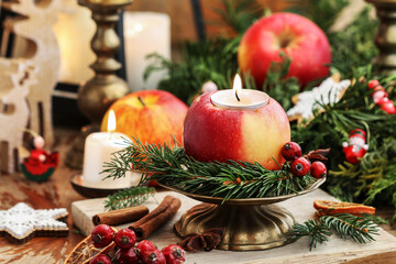 Traditional Christmas decoration with apples, cinnamon sticks and candles.