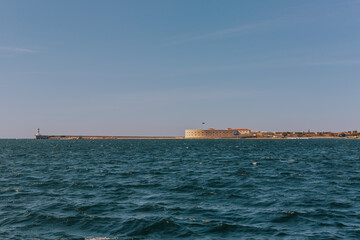 Fototapeta premium Konstantinovskaya battery, and a pier with a lighthouse at the exit from Sevastopol Bay in the Black sea