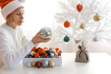A pretty woman decorates a beautiful white Christmas tree, holidays, celebration and people concept