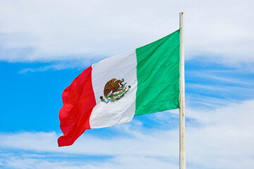 Mexican flag waving against the blue sky in Mexico
