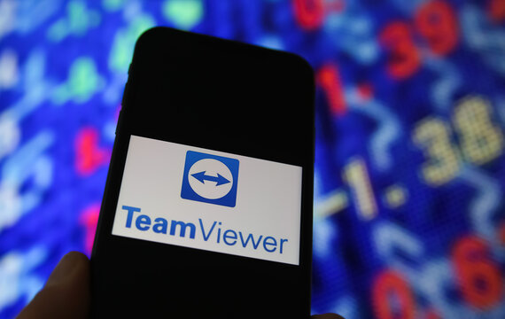 Viersen, Germany - June 6. 2021: Closeup of mobile phone screen with logo lettering of teamviewer, stock market chart background