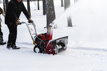 Men remove snow in the park with a snow blower