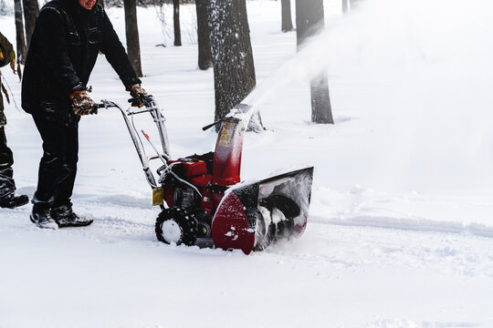 Men remove snow in the park with a snow blower