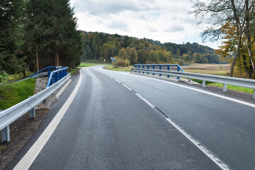 Fototapeta premium A new bridge across a small river. Summer time. Small reinforced concrete bridge after reconstruction. New asphalt.