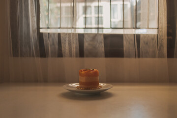 Orange fruit cake dessert in a cup served on white dish.