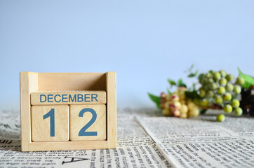 December 12, Calendar cover design with number cube with fruit on newspaper fabric and blue background.	
