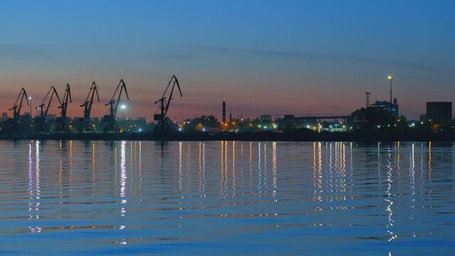 Russia, Nagatinsky zaton, 11.05.2021, Night embankment with the reflection of city lights in the water against the background of port cranes and a lighthouse.