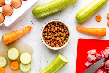 Dogfood set with cut vegetables and knife on table background top view