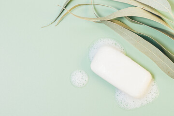 Soap bar with foam next to eucalyptus leaves