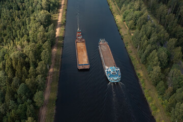 Aerial view of two barges diverging along a narrow channel in opposite directions