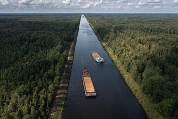 Aerial view of two barges diverging along a narrow channel in opposite directions