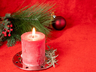 Red Christmas candle and Christmas decorations on a red background.