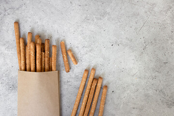 Bread sticks, with sesame seeds and whole grain flour on grey background. Top view, copy space.