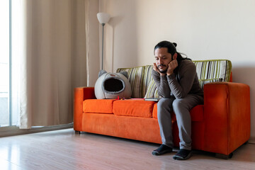 Young man sitting in the couch alone at home in the living room