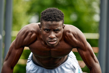 Working out in the morning. Young strong african man in sportswear exercising outdoors. Sport, training concept. Healthy active lifestyle. TRX