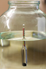 alcohol meter in a glass of moonshine. Wine meter for determining the percentage of alcohol.